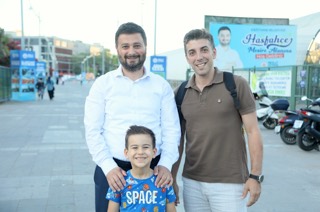 Mevlüt Öztekin bir mesire alanının girişinde, önündeki gülen çocuğun omuzlarına ellerini koymuş, yanında bir adam var.