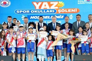 Mevlüt Öztekin sahnede madalyalı ve sertifikalı sporcu çocuklar ve protokol üyeleriyle toplu fotoğrafta.
